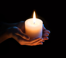 Women's hands holding a candle