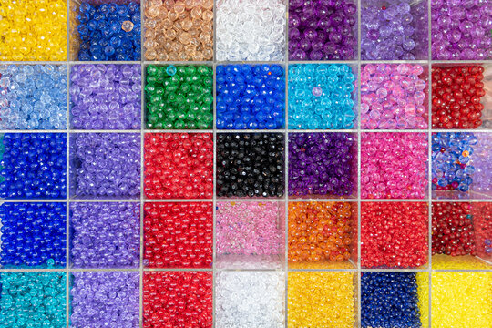 Beads are arranged and sorted by color. Background of colorful bright beads in boxes, set for needlework. High quality photo