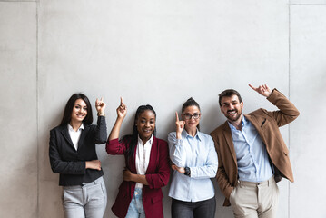 Group of young happy successful business team people pointing finger up and smiling. Freelancers or...