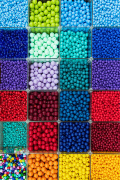 Beads are arranged and sorted by color. Background of colorful bright beads in boxes, set for needlework. High quality photo