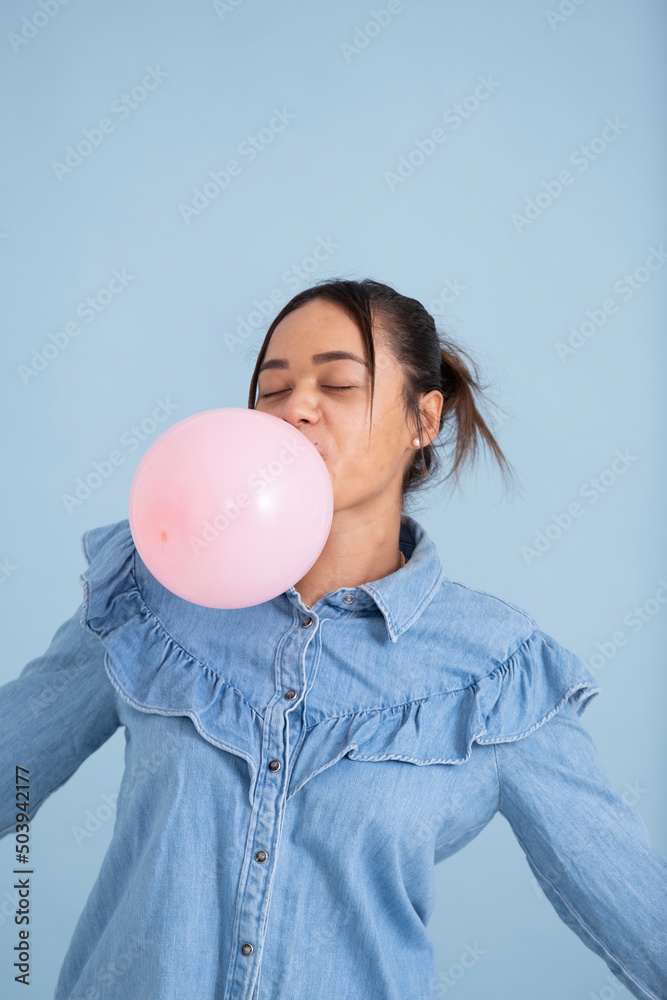 Wall mural Studio shot of young woman chewing gum and blowing bubble - Wall murals