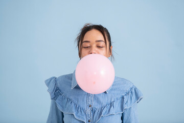 Studio shot of young woman chewing gum and blowing bubble