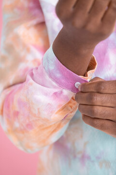 Studio shot of mid adult woman buttoning multi-colored shirt, close up of hands