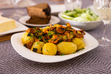baked potatoes with chanterelles, served with herbs on white plate