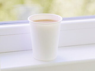 A cup of coffee is on the windowsill. Breakfast. Coffee to go