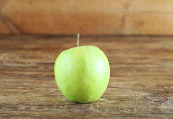One green apple lies on a wooden table. Morning in the village