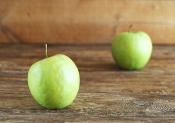 Two green apples lie on a wooden table. Rustic style