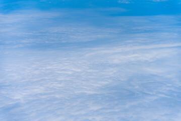 飛行機の窓から眺める空の景色　青空と流れる白い雲