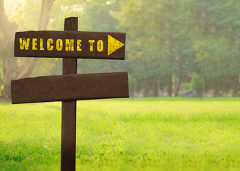 Wooden signs welcome on a natural green background copy space.