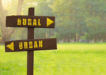 Wooden signs Rural versus Urban on a natural green background copy space.