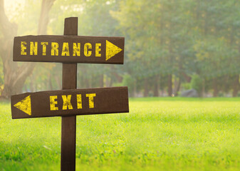 Wooden signs Entrance versus Exit on a natural green background copy space.
