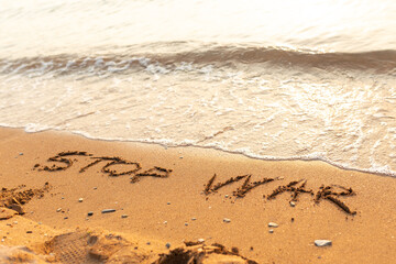 Words written in the sand on the beach. The words Stop War and written in the Sand with the Ocean in the background. Protest War sign written in sand. World Peace. No War