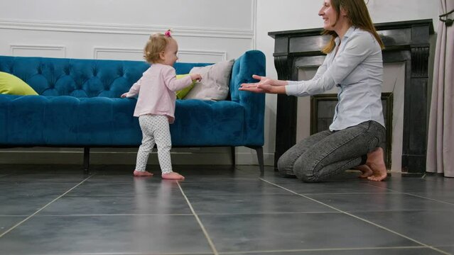 Little baby girl learn to walk, making first steps with mother
