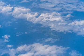 飛行機の窓から眺める空の景色　青空と流れる白い雲
