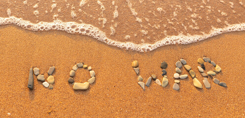 Words written in the sand on the beach. The words No War and written in the Sand with the Ocean in the background. Protest War sign written in sand. World Peace. No War