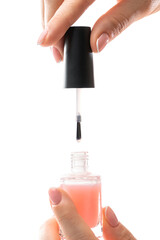 Female hands with beautiful french manicure holding bottle of pink nail polish against white background