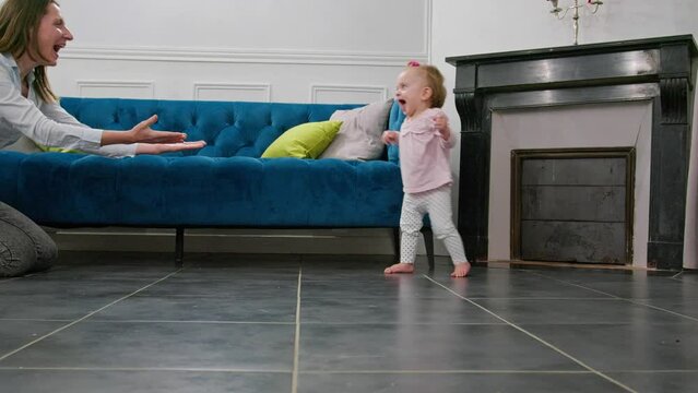 Excited mother help little baby girl to make first steps