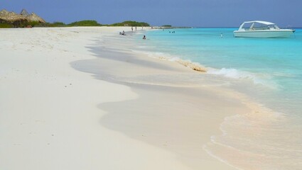 beach landscape with sandy shoreline and turquoise waters and a white boat, unrecognizable sunbathers in the background; Klein Curacao 
