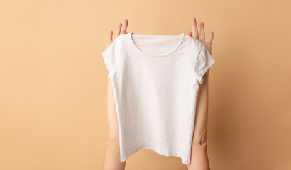Female hands holding a white t-shirt close-up. Mock-up