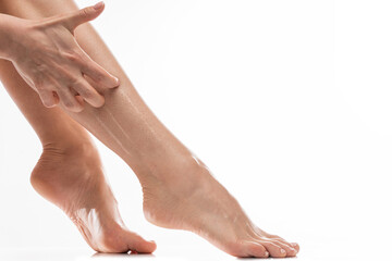 Female legs with dry itchy skin against white background