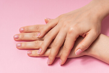 Female hands with soft skin and beautiful french manicure against pink background