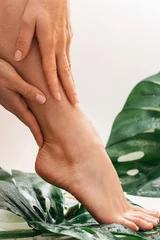 Keuken foto achterwand Wet female feet with smooth skin and Monstera deliciosa tropical leaf © blackday
