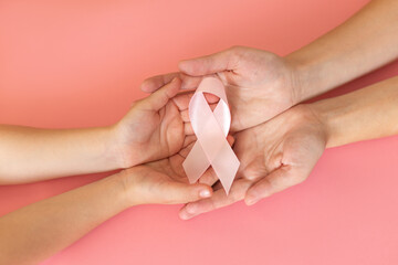 Hands holding pink ribbon on pink background, Breast cancer awareness and October Pink day, world...