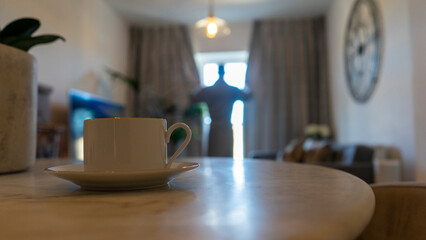 Man in living room, focus on coffee cup in foreground