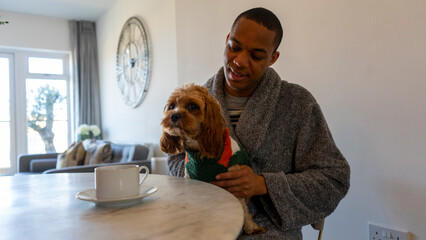 Man sitting at table and holding dog on lap