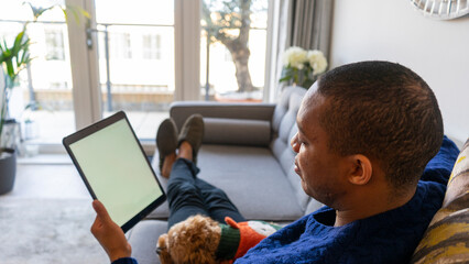 Man sitting on sofa using digital tablet © Cultura Creative