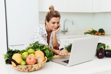 Young pretty woman using laptop for online recipe search to cook at home