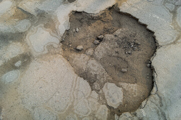 A pit in the road. Damaged asphalt. Destroyed and poor condition road surface. A pit on the asphalt. Selective focus
