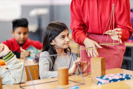 A teacher showing geometry to a pupil in classroom.