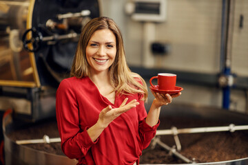 A happy woman in coffee factory presenting high quality fresh coffee.