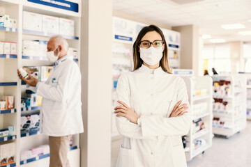 A young pharmacy worker proudly standing and looking at the camera during corona virus.