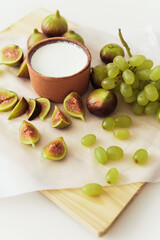 Delicious natural Greek yogurt in clay bowl with figs and grape