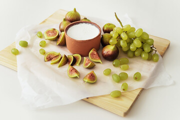 Delicious natural Greek yogurt in clay bowl with figs and grape