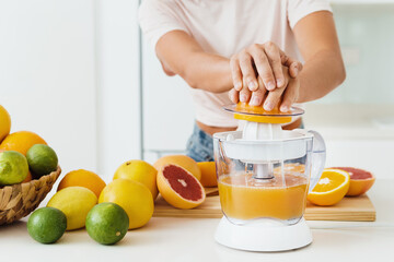 Female hands and citrus juicer during fresh orange juice preparation