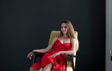 Fototapeta na wymiar portrait of a young woman in a red dress sitting on a chair