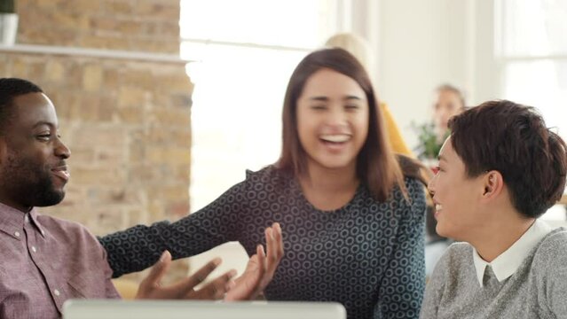 A group of businesspeople brainstorming during a meeting. A diverse group of corporate businesspeople planning during a meeting, talking and laughing. A group of happy businesspeople talking