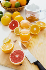 Sliced citrus fruits and glass of fresh orange juice on the cutting board