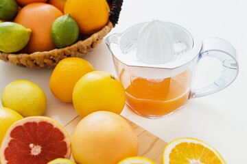 Juicer and various citrus fruits on white kitchen table