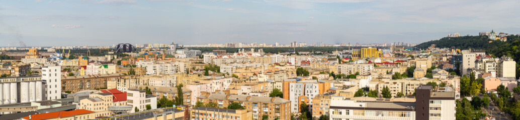 Fototapeta na wymiar Kyiv, Ukraine – July 08, 2017: A beautiful panorama of Podil area. Aerial view on residential and industrial areas. A lot of buildings of different architectural style. Historical area, Dnipro river.