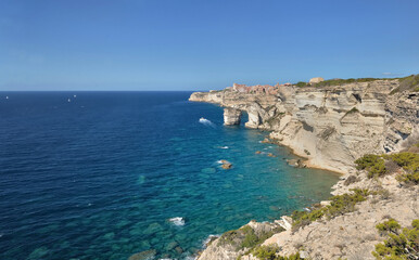 Fototapeta na wymiar Bonifacio coastline with limestone cliff overlooking the sea on clear blue sky