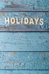 Holidays text word written on wooden letters on a textured blue wooden board