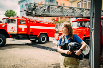 Obraz na płótnie Canvas Female firefighter in protective uniform standing near red fire truck