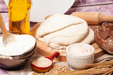 Baking ingredients and kitchen utensils. Culinary background with bread,flour,fresh dough, sunflower oil, dry yeast, salt, ,ears of wheat, rolling pin.