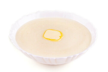 Semolina porridge with a piece of butter in a plate on a white isolated background. Side view.