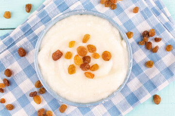 Semolina porridge in a bowl (plate) with raisins on a blue cloth napkin close-up.