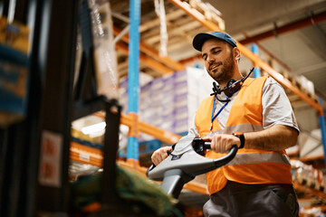 Warehouse worker moving packages with pallet jack while working at storage compartment.